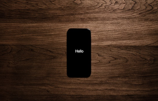 Smartphone negro con fondo de madera con HELLO en blanco en la pantalla
